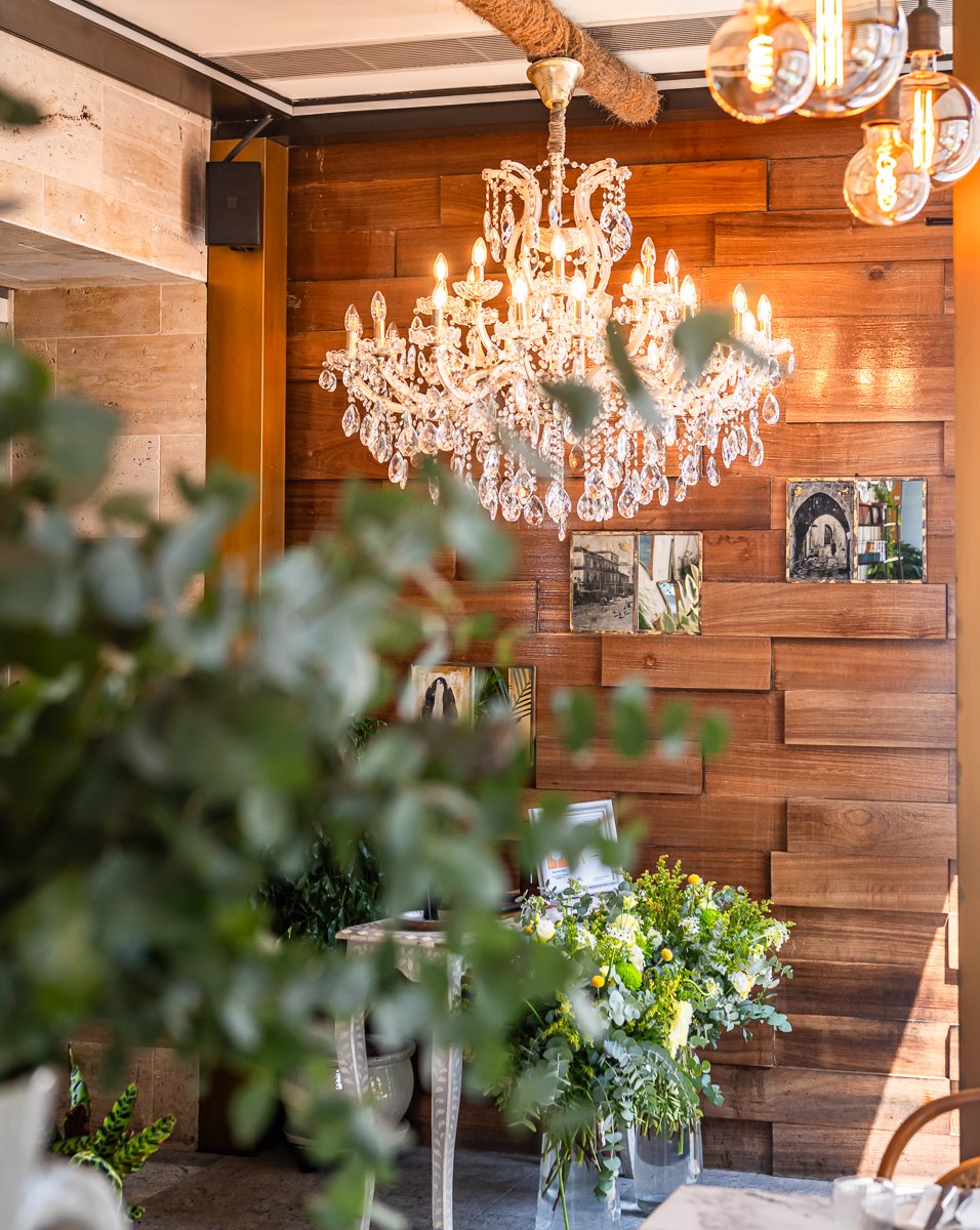 Villa Mamas Abu Dhabi crystal chandelier above a reclaimed wood photo wall