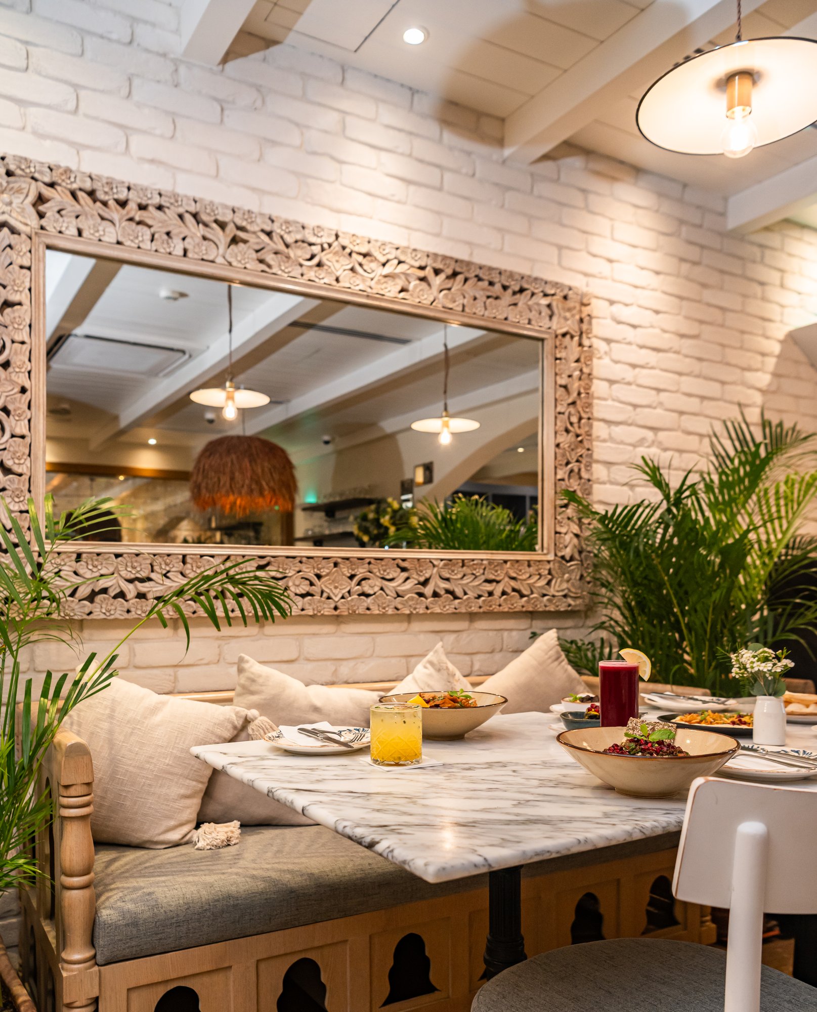 Villa Mamas Abu Dhabi marble table set beneath a carved wooden mirror