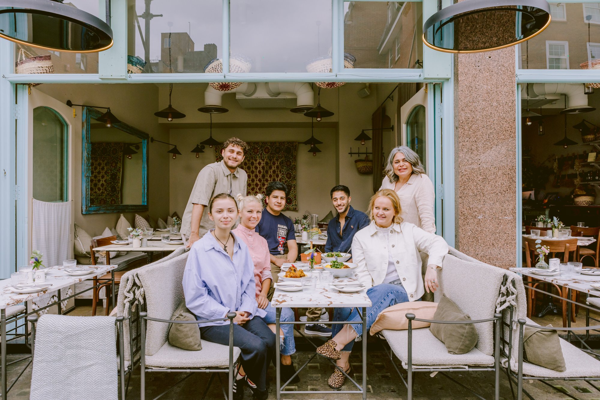 The Villa Mamas London team gathered at a table by the restaurant front