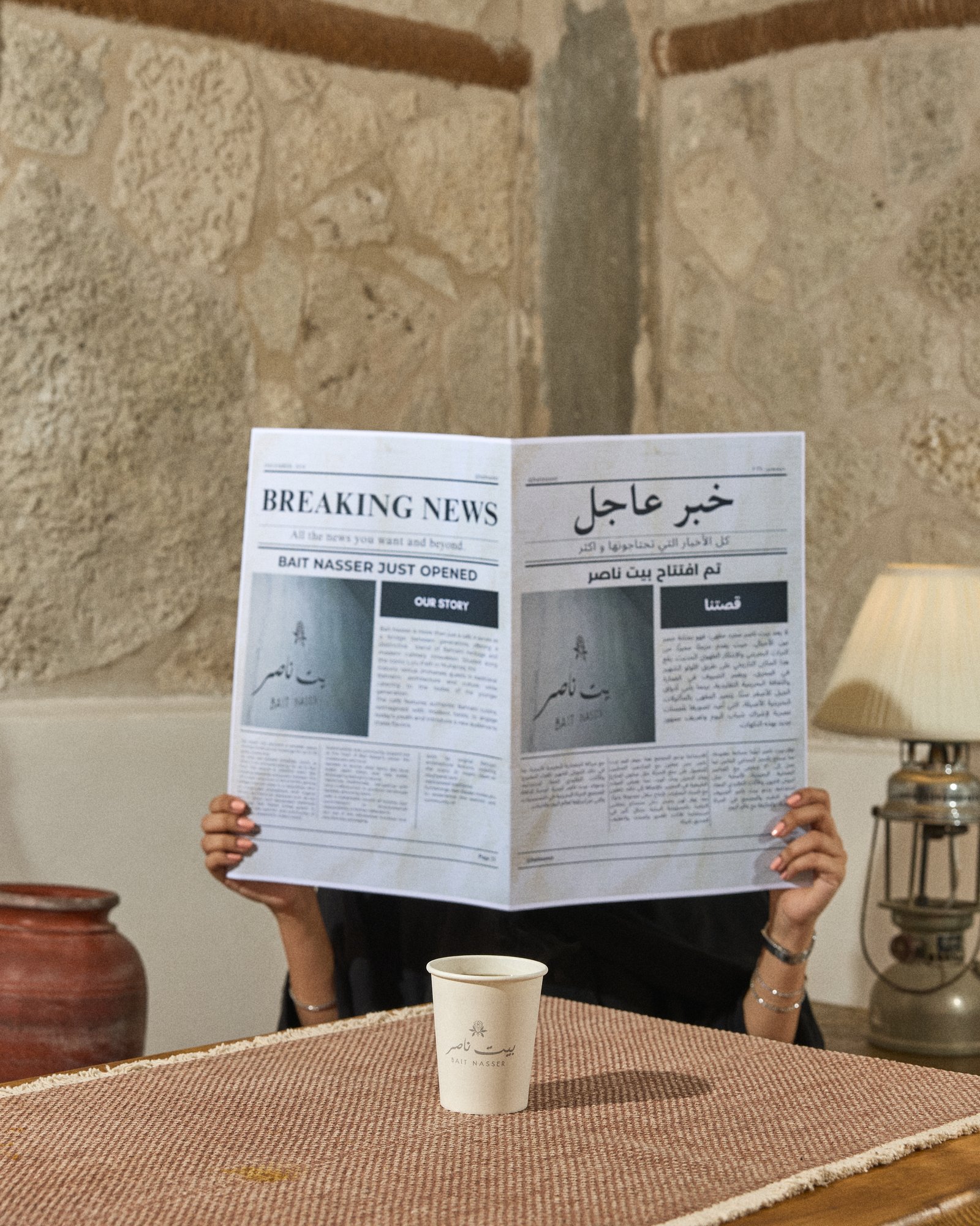 A guest reading the Bait Nasser newspaper with a coffee cup on the table